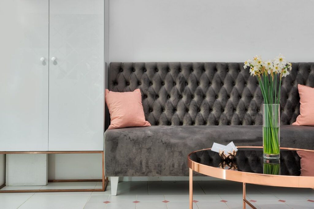 Interior design of modern lobby of clinic with sofa and stylish table decorated with bunch of daffodils in vase